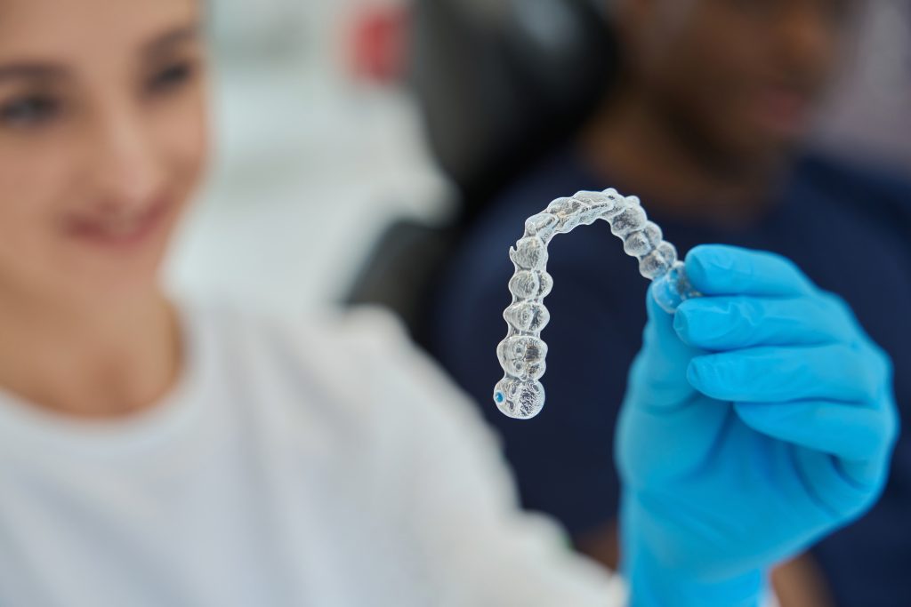 Dental technician holding invisible braces, or clear aligners