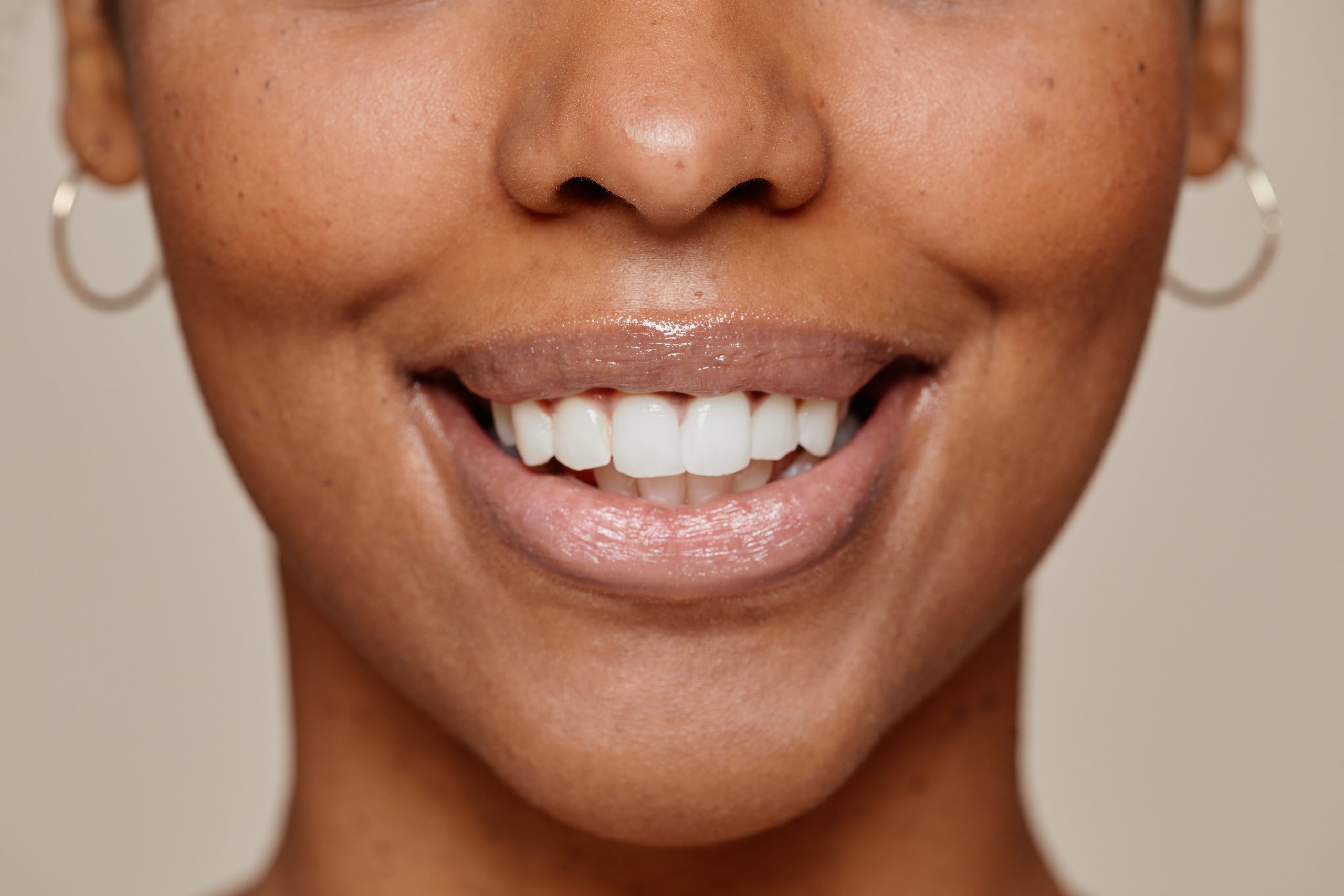 Close up portrait of young African-American woman smiling at camera demonstrating beautiful natural skin and white over bite smile